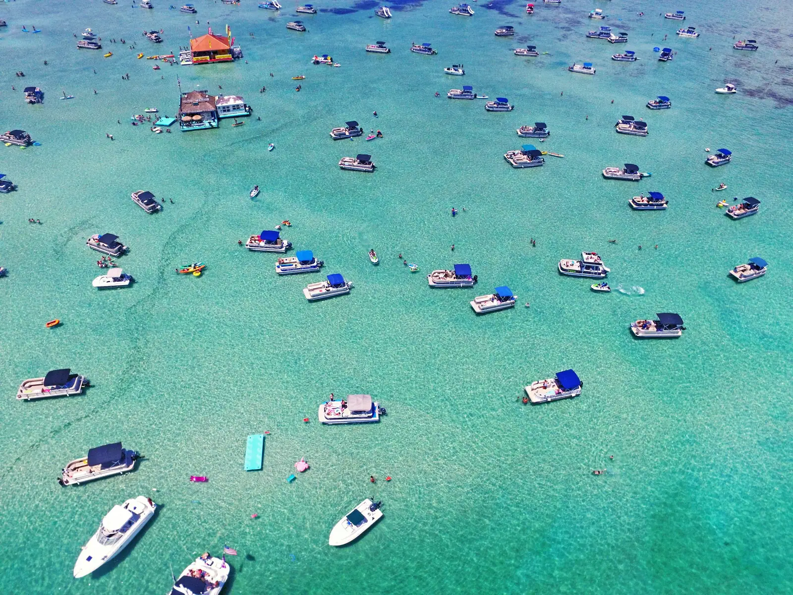 Boats anchored at a sandbar in clear green water off Destin, seen from above