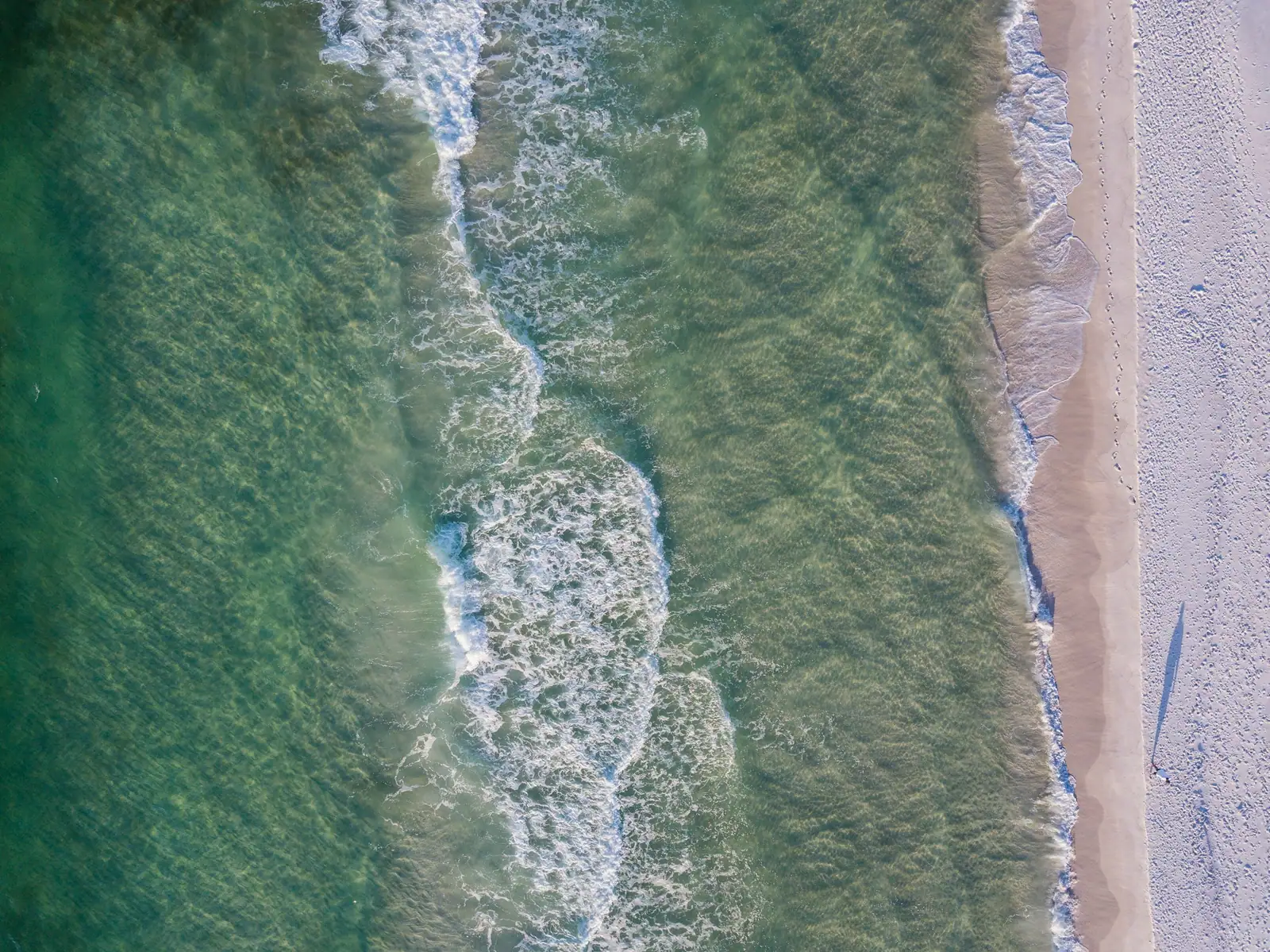 Looking straight down at waves washing onto the sand at Pensacola Beach